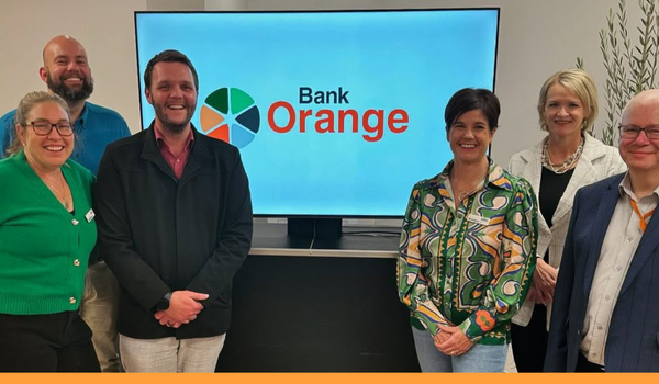 Representatives of Business Orange and Bank Orange standing around a screen with Bank Orange's logo on it.