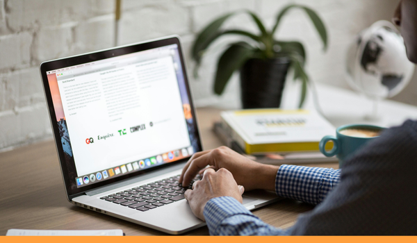 man reading an email newsletter. Only his arms are visible, the rest of the image shows the laptop and desk.